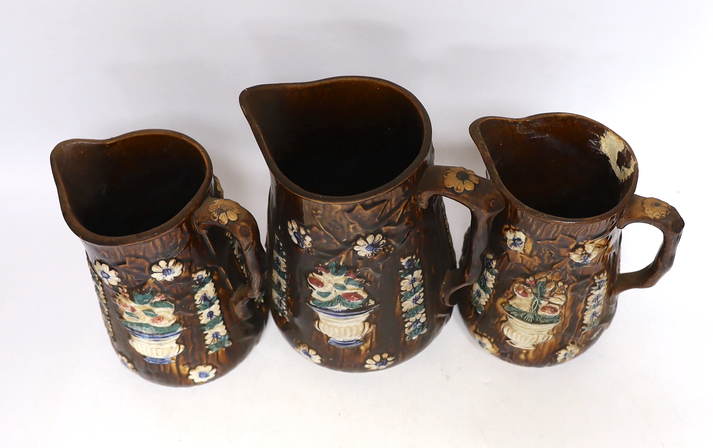 Three Measham barge ware glazed pottery jugs, decorated in relief, largest 22cm high
